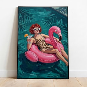 Op de afbeelding: Ingelijst kunstwerk toont een vrouw in een luipaardprint badpak en zonnebril, ontspannen op een roze flamingo zwemband. Ze houdt een cocktail met een sinaasappelschijfje vast. De achtergrond is een turquoise zwembad met palmbladeren.