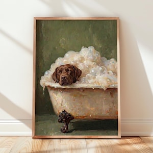 Könnte beinhalten: Ein gerahmter Kunstdruck, der einen braunen Labrador-Hund zeigt, der in einer Vintage-Badewanne mit Klauenfüßen ruht, die mit dicken weißen Seifenblasen gefüllt ist. Der Hintergrund ist einfarbig olivgrün und die Wanne hat dunkle, verzierte Füße.