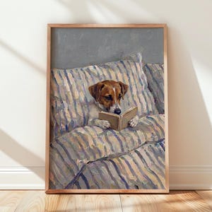 Könnte beinhalten: Ein gerahmter Ölgemäldedruck, der einen braun-weißen Jack Russell Terrier zeigt, der auf einem Bett mit gestreifter Bettwäsche sitzt. Der Hund hält ein offenes Buch mit seinen Vorderpfoten und schaut auf die Seiten. Der Hintergrund ist eine graue Wand.