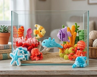 May include: A clear glass aquarium filled with crocheted sea creatures and coral. The aquarium contains a variety of colorful fish, octopuses, and starfish, along with coral and plants. The scene is set on a wooden table.