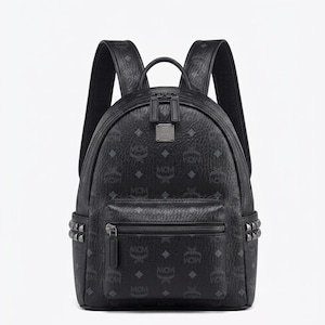 Könnte beinhalten: Schwarzer Rucksack mit strukturierter Oberfläche und sich wiederholendem Logo-Muster. Der Rucksack hat eine Reißverschlusstasche vorne, Nieten und verstellbare Schultergurte. Eine kleine Metallplakette befindet sich mittig über der Tasche.