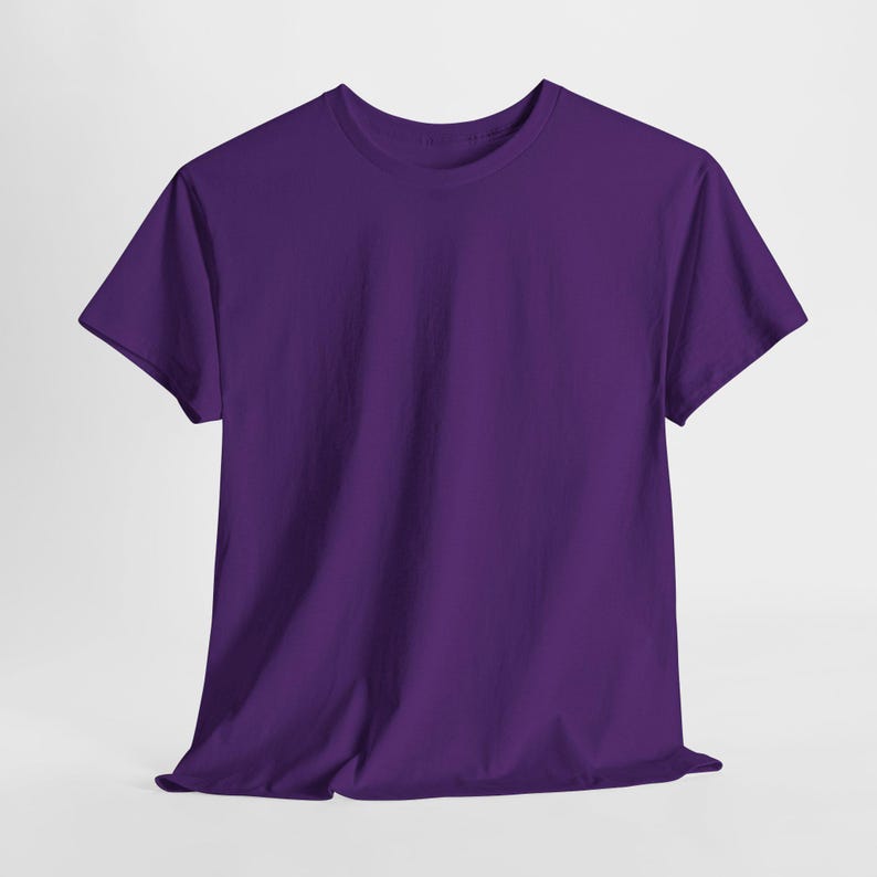 May include: A solid purple t-shirt with a crew neck and short sleeves. The shirt is made of a soft material and is displayed on a neutral background. The fabric drapes naturally, showcasing the garment's shape.