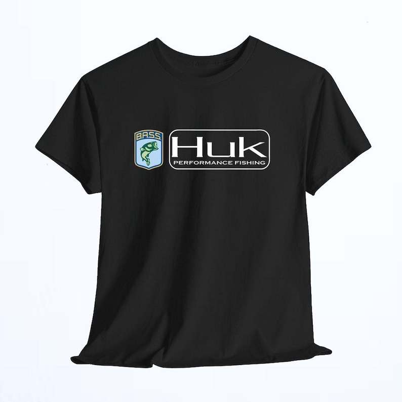 May include: A black short-sleeved t-shirt featuring a graphic on the chest. The graphic includes a blue shield with a green fish and the word BASS, next to a white rectangular logo with the text Huk PERFORMANCE FISHING in a bold font.
