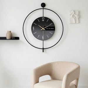 Modern minimalistisk väggklocka med pendel – svart cirkulär design med guldfärgade visare