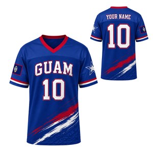May include: A blue V-neck jersey featuring the word GUAM and the number 10 in white with red outlines on the front. The sleeves have red, white, and blue stripes, a star graphic, and the Guam flag. The back displays YOUR NAME and number 10.