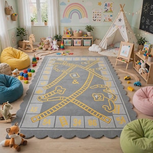 Op de afbeelding: Een rechthoekig grijs vloerkleed met een geschulpte rand en een geel bordspelontwerp met genummerde vakjes, ladders en kronkelende paden. Het kleed ligt op een houten vloer in een speelkamer vol met speelgoed en zitzakken.