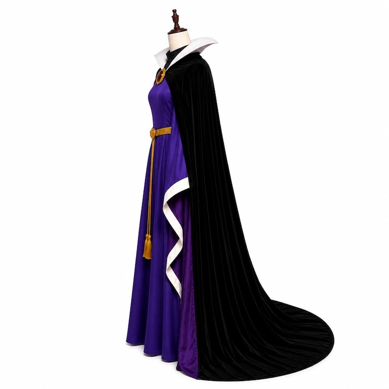 May include: A floor-length purple dress with a high black collar and a long black velvet cape. The dress features a gold-colored belt with a hanging tassel, a white stand-up collar, and a circular red brooch at the neckline of the cape.