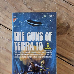 May include: A vintage paperback science fiction book cover with a blue background and a flying saucer. The title is "The Guns of Terra 10" by Don Pendleton. The cover features a group of people running on a rocky surface.
