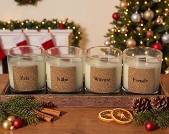 May include: Four clear glass candles with white wax and wooden wicks, each featuring a square cork label with the German words Zeit, Nähe, Wärme, and Freude printed in black, arranged in a rectangular wooden tray.