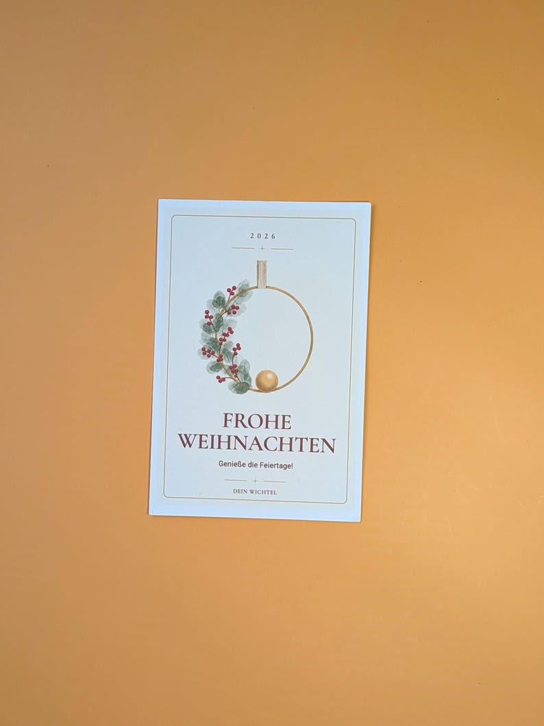 May include: A rectangular white card featuring the text 2026, FROHE WEIHNACHTEN, Genie&szlig;e die Feiertage!, and DEIN WICHTEL. The design includes a gold hoop decorated with green leaves, red berries, and a small gold sphere at the bottom centre.