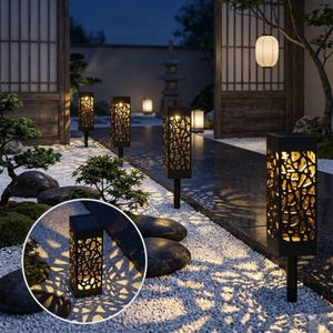 Könnte beinhalten: Schwarze Solar-Gartenleuchten mit dekorativem Ausschnitt-Design. Die Leuchten sind rechteckig und auf Pfählen montiert und beleuchten einen Weg mit warmem Schein. Die Leuchten befinden sich in einem Garten mit japanischer Ästhetik.