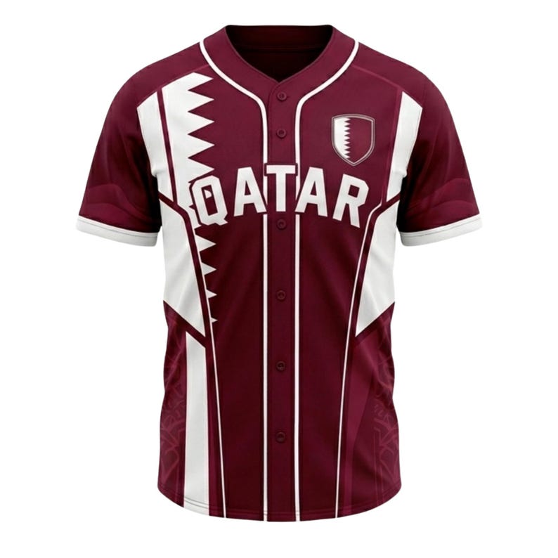 May include: Maroon baseball jersey with white detailing and the word "QATAR" across the chest. The jersey has a button-up front, short sleeves, and a shield emblem on the right chest.