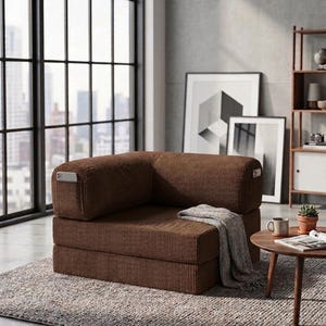 May include: A brown corduroy modular floor chair featuring a low-profile, boxy design with a corner backrest. The fabric has a distinct vertical ribbed texture. A small side pocket is integrated into the armrest, and a grey throw blanket is draped.
