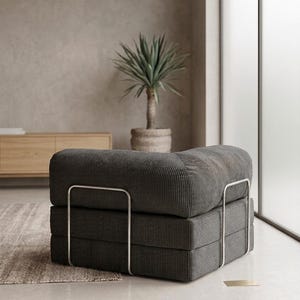 May include: A low-profile, square-shaped modular chair upholstered in dark gray corduroy fabric. The seat features a thick, cushioned design supported by a sleek, silver-toned metal frame that wraps around the sides and base of the furniture piece.