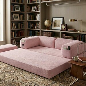 May include: A low-profile, pink corduroy modular sofa bed featuring a wide, flat seating area, two back cushions, and integrated side pockets for storage. The sofa includes a matching rectangular ottoman positioned to the left of the main unit.