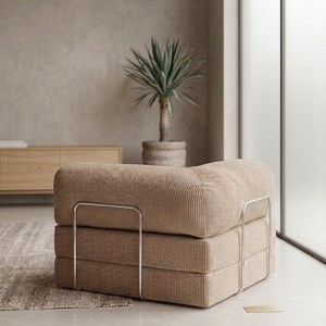 May include: A low-profile modular armchair upholstered in beige corduroy fabric. The seat features a thick, square cushion design supported by a sleek, silver-toned metal frame that wraps around the sides and back of the furniture piece.