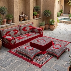 May include: A floor seating set featuring a long sofa, a square ottoman, and two rectangular floor cushions, all upholstered in red fabric with intricate black and white geometric patterns, arranged on a matching red fringed area rug.