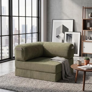 May include: A low-profile, olive green corduroy modular chair featuring a square, armless design with integrated side pockets. The seat is composed of thick, stacked foam cushions and is draped with a light gray textured throw blanket.