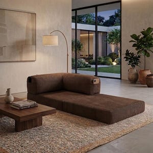 May include: A low-profile, brown corduroy modular sofa with a corner backrest and integrated side storage pockets. The sofa is positioned on a textured rug next to a low wooden coffee table, featuring a clean, rectangular design and firm cushions.