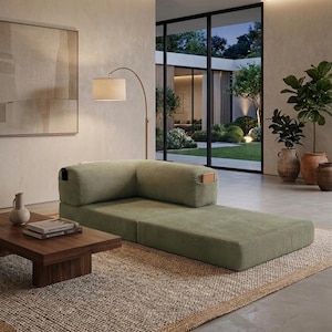 May include: A low-profile, sage green corduroy floor sofa featuring an L-shaped backrest with integrated side pockets. The modular seating unit is upholstered in a textured ribbed fabric and sits directly on a woven area rug in a neutral tone.
