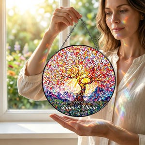 Può includere: Pannello rotondo in vetro colorato raffigurante un albero colorato su uno sfondo montuoso. L'opera d'arte include il testo "60th Anniversary Liam & Olivia 1-27-1966" ed è sospesa da una catena.