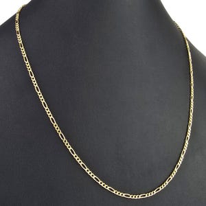 K&ouml;nnte beinhalten: Eine Figaro-Halskette aus Gelbgold mit einem sich wiederholenden Muster aus drei kleinen runden Gliedern, gefolgt von einem l&auml;nglichen ovalen Glied. Die Metallkette hat eine polierte Oberfl&auml;che und ist als durchgehende Schlaufe dargestellt.