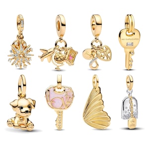 May include: A collection of gold-colored charms, including a snowflake, airplane with globe, heart, key, puppy, key with pink stone, butterfly wing, and a tea kettle charm. Each charm has a loop for attaching to a bracelet or necklace.