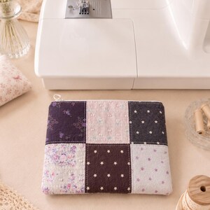 Könnte beinhalten: Eine rechteckige Stofftasche mit einem Patchwork-Design aus sechs Quadraten. Die Muster umfassen Dunkellila mit Schmetterlingsmotiven, Hellrosa mit kleinen Punkten, Dunkelgrau mit weißen Sternen, florale Drucke in Flieder und Braun mit weißen Sternen.
