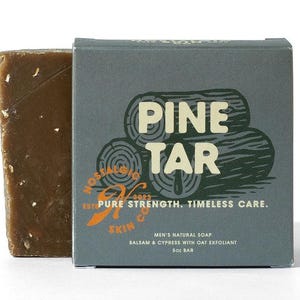 May include: A bar of pine tar soap and its box are displayed against a white background. The box is gray with the words "PINE TAR" in large white letters. The soap is dark brown and has a rough texture. The box also says "MEN'S NATURAL SOAP" and "5 oz BAR".