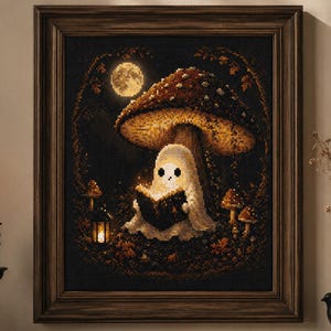 Op de afbeelding: Een ingelijst kruissteekkunstwerk toont een spook dat onder een paddenstoel leest, met een volle maan en een lantaarn. Het kleurenpalet omvat bruin-, zwart- en wittinten, waardoor een gezellige, spookachtige sfeer ontstaat. Een charmant stuk gothic-thema decor.