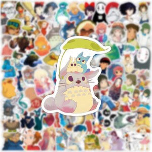 May include: A collection of anime-themed stickers featuring various characters. The central sticker showcases a gray, fluffy creature with a yellow belly, topped with two smaller blue and yellow figures, all under a green leaf.