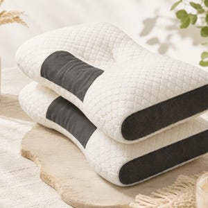 May include: Two stacked ergonomic pillows featuring a white quilted top surface with a repeating hexagonal pattern. Each pillow has a dark gray rectangular panel on the side and a dark gray mesh fabric along the bottom edge for ventilation.