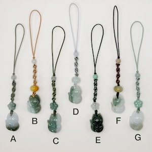 May include: A collection of seven jade fox pendants, each with a different colored cord and bead accents. The foxes are carved in various shades of green and white, with some featuring yellow or brown beads. The pendants are labeled A through G.