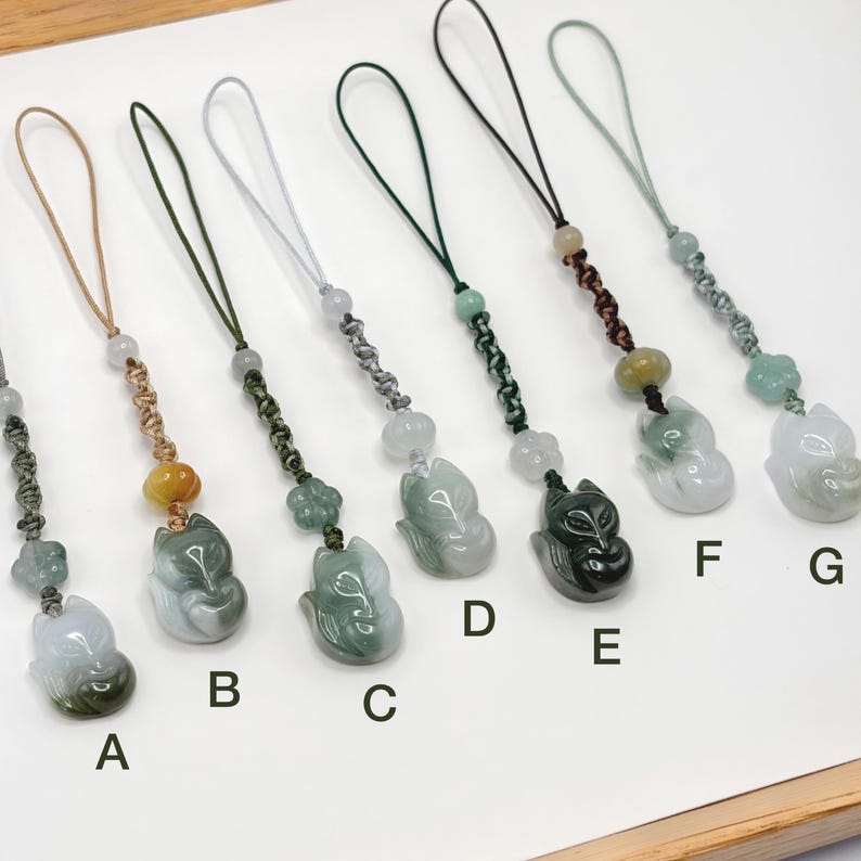 May include: A collection of seven jade fox pendants with various cord colors. Each pendant is a carved fox figure with a loop for attachment. The colors of the jade vary from light green to dark green.