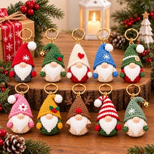 May include: Ten crocheted gnome keychains arranged in two rows on a wooden surface. Each gnome features a unique hat design, including solid colours, stripes, and patterns like snowflakes, hearts, and flowers, with a white beard and gold ring.