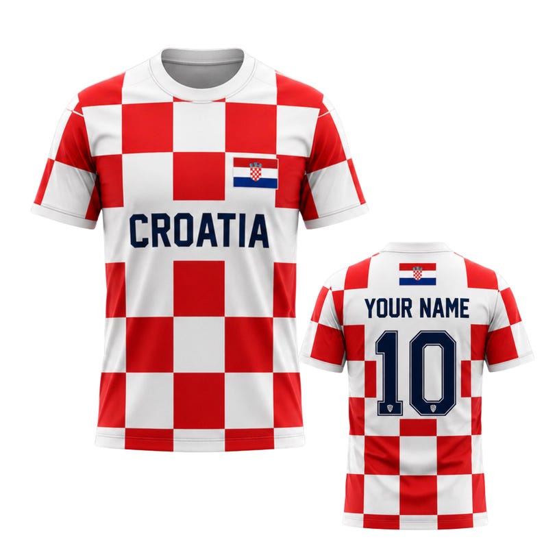 Może przedstawiać: Biało-czerwona koszulka piłkarska Chorwacji w kratkę. Z przodu koszulki napis "CROATIA" w kolorze granatowym oraz chorwacka flaga. Z tyłu napis "YOUR NAME" nad numerem "10" w kolorze granatowym.