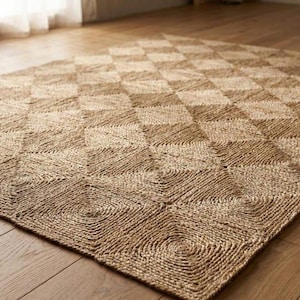 May include: A rectangular area rug crafted from natural tan fibres, featuring a repeating geometric pattern of squares composed of concentric circular coils. The woven texture is consistent throughout the surface, creating a grid of diamond shapes.