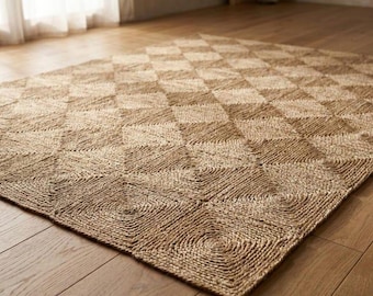 May include: A rectangular area rug crafted from natural tan fibers, featuring a repeating geometric pattern of squares composed of concentric circular coils. The woven texture is consistent throughout the surface, creating a grid of diamond shapes.