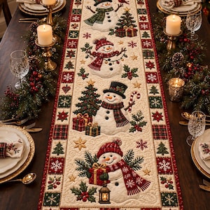 May include: A rectangular quilted table runner featuring a cream-colored center panel with four distinct snowman figures, decorated with Christmas trees, wrapped gifts, holly, and stars, framed by a red and green border with snowflake patterns.