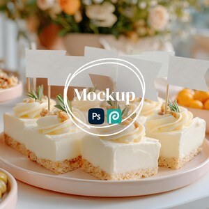 May include: A plate of cheesecake squares topped with whipped cream, nuts, and sprigs of rosemary. Each square has a small white flag on a wooden stick. The word "Mockup" is in the center of the image.
