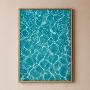 Könnte beinhalten: Ein rechteckiger Wandkunstdruck mit einer Draufsicht auf klares, türkisfarbenes Schwimmbadwasser. Die Oberfläche zeigt komplexe weiße kaustische Lichtmuster, die durch das Sonnenlicht entstehen, das sich in den Wasserwellen bricht.