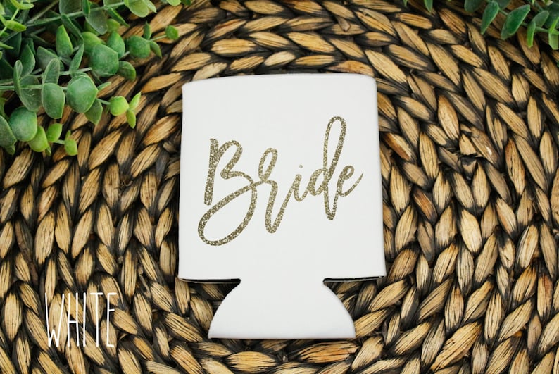Puede incluir: Enfriador de latas blanco con la palabra "Bride" escrita en letras doradas con purpurina.