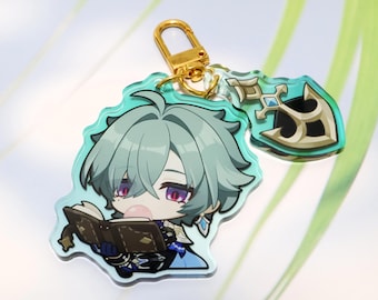 Può includere: Un portachiavi in acrilico raffigurante un personaggio in stile chibi con capelli verde chiaro e occhi rossi, intento a leggere un libro marrone. Il ciondolo include un moschettone in metallo dorato e un piccolo charm a forma di scudo.