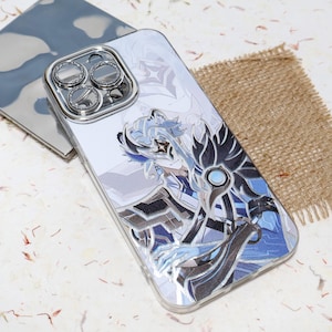 May include: A clear smartphone case featuring a printed graphic of a stylised anime character with blue hair, a white mask, and dark armour accents. The case includes a metallic silver camera lens protector frame with circular cutouts for three lenses.