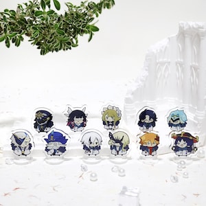 May include: A collection of small, colorful acrylic character figures. Each figure features a unique design with detailed outfits and expressions. The figures are displayed on clear stands, creating a floating effect. The background includes greenery and a white architectural element.