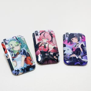 May include: Three rectangular anime-style badges featuring colorful illustrations of female characters. The badges have a glossy finish and are set against a white background. Each badge showcases a unique character design with vibrant colors and detailed artwork.