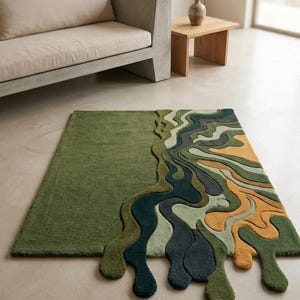 Könnte beinhalten: Ein rechteckiger Teppich mit einem einfarbigen olivgrünen Bereich auf der linken Seite und einem mehrfarbigen, wellenförmigen, flüssigkeitsartigen Muster auf der rechten Seite. Das Design umfasst Schattierungen von Dunkelgrün, Salbei, Hellgrün und Senfgelb.