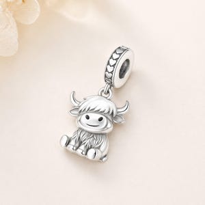Pode incluir: Um berloque de prata com um design de vaca das Terras Altas. O berloque tem um rosto sorridente, pequenos chifres e um casaco fofo. A parte superior do berloque tem um design em forma de cora&ccedil;&atilde;o. Este berloque &eacute; uma &oacute;tima adi&ccedil;&atilde;o.