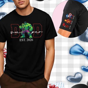 Può includere: T-shirt nera con grafica di Hulk che tiene un bambino, la parola "DAD" in rosso e la parola "super" in corsivo bianco. Il testo "EST. 2026" è sotto. La manica ha icone di supereroi.