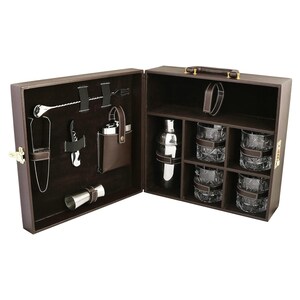 Op de afbeelding: Een bruine koffer in lederlook met een barset. Het interieur bevat een zilverkleurige cocktailshaker, vier glazen met kristalpatroon, een metalen jigger, een kurkentrekker, een ijstang, een lange menglepel en een metalen heupfles in een etui.